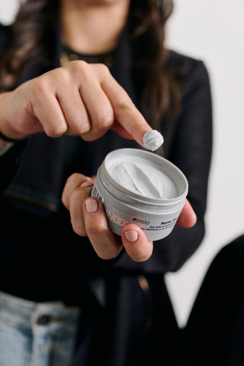 een vrouw die een beetje wax uit een potje van Indola Matte Wax haalt met haar vinger